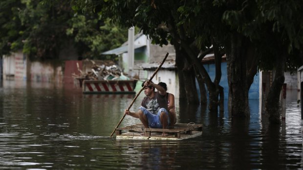 A couple drive a makeshift raft on a flooded street in Asuncion, Paraguay.