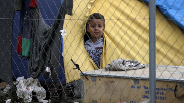 A boy looks from a tent in a makeshift refugee camp in the Idomeni camp