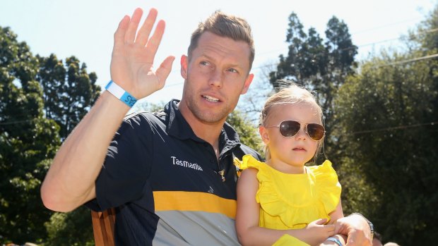 Sam Mitchell holds his daughter as he waves to the crowd during the AFL grand final parade on Friday.