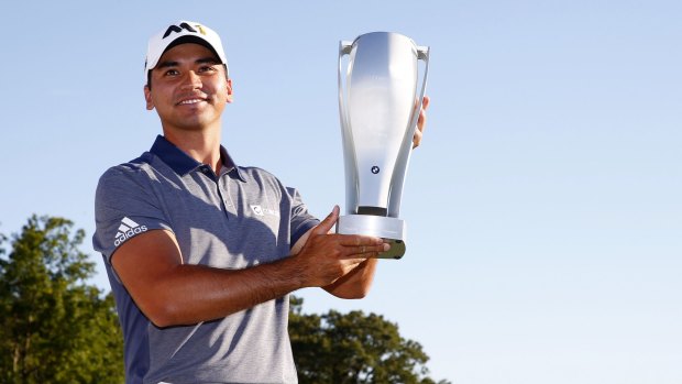 Jason Day celebrates with the winner's trophy.