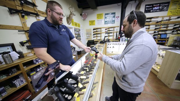 Mike Howse, left, helps David Foley as he shops for a handgun in Spring, Texas. Not even the White House pretends that President Barack Obama's latest moves will make much of a dent in America's annual toll of 30,000 gun deaths.
