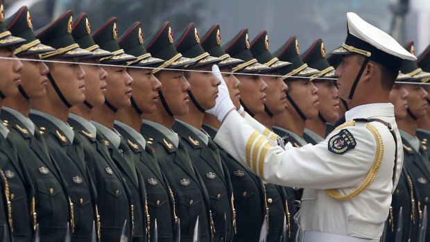 An officer of the PLA uses string to ensure the soldiers in a guard of honour stand in a straight line before an official welcoming.