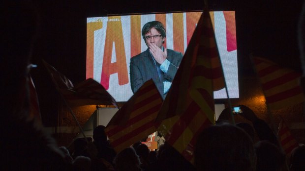 Ousted Catalan president Carles Puigdemont sends a kiss to his supporters as he appears via video link from Brussels on Tuesday. 