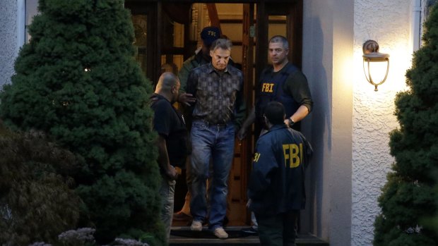 Former hedge fund manager Vitaly Korchevsky is escorted in handcuffs from his home by FBI agents.