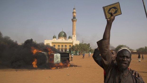 A man holds a copy of the Koran during a protest in Niamey at the weekend, after Niger's President Mahamadou Issoufou attended the mass rally in support of <i>Charlie Hebdo</i> in Paris.