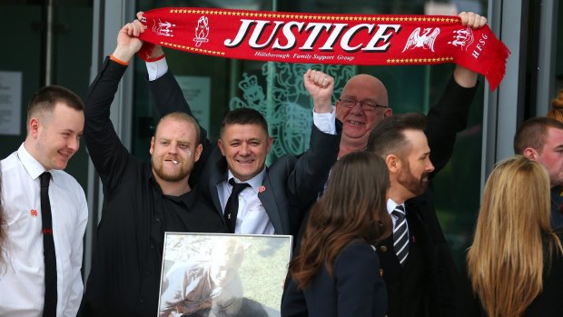 Relatives of the Hillsborough victims hold up a "Justice" scarf as they depart Birchwood Park after hearing the conclusions of the Hillsborough inquest on April 26, 2016.