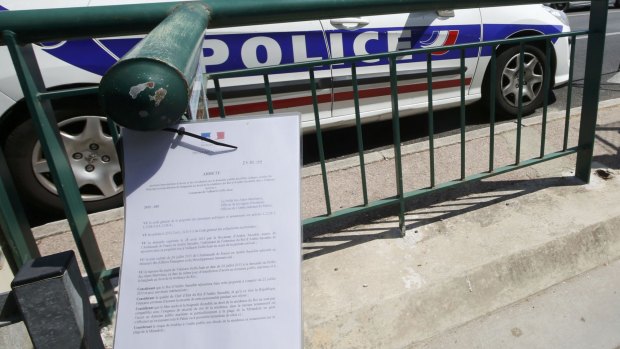A French police car is parked near an official document from the Prefecture informing the public of the closure of the La Mirandole beach.