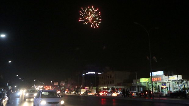 Fireworks explode in the sky as Iraqi Kurdish men celebrate in the streets after polls closed in Idlib, Iraq, on Monday.