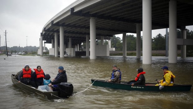Rescuers in boats and kayaks  help trapped residents escape.