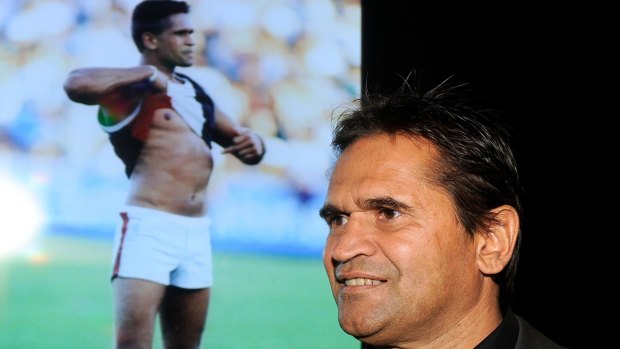 Nicky Winmar in 2013, with the famous picture of him confronting abusive Collingwood fans 20 years earlier.