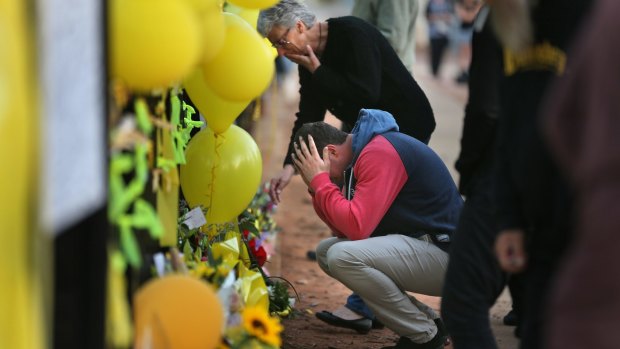 Stephanie Scott's mother, Merrilyn Scott, and Aaron Leeson-Woolley, Stephanie's fiance, at the floral memorial on the gates of the high school where she worked. 