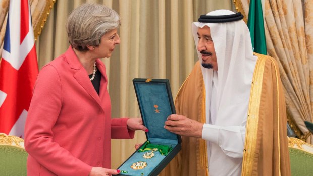 In this photo released by Saudi Press Agency, SPA, Saudi King Salman, right, presents a gift to British PM Theresa May.