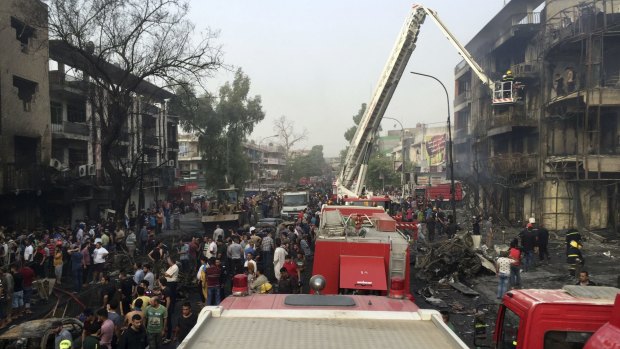 Iraqi security forces look for victims as civilians gather at the explosion site.