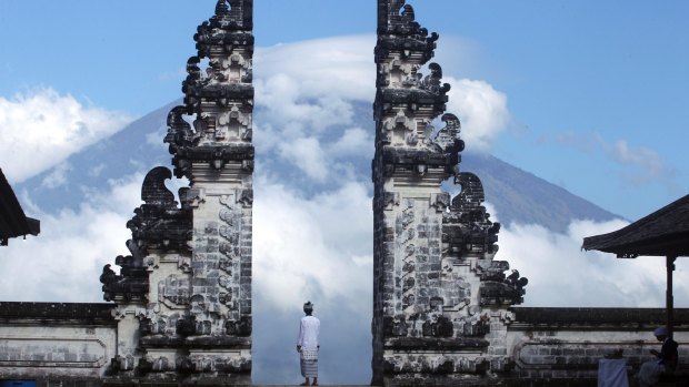 A Balinese man watches Mount Agung volcano almost covered with clouds as he stands at a temple in Karangasem.