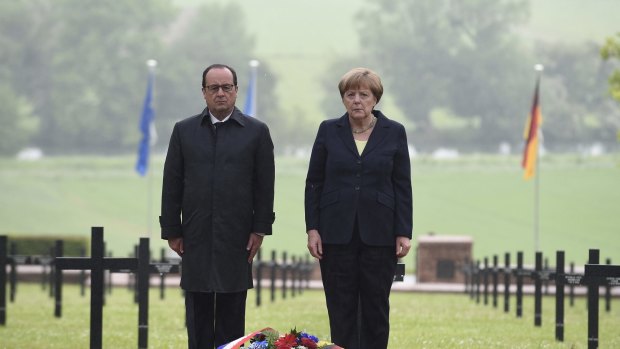 French President Francois Hollande and German Chancellor Angela Merkel pay their respects after laying a wreath at a German cemetery in Consenvoye, northeastern France.