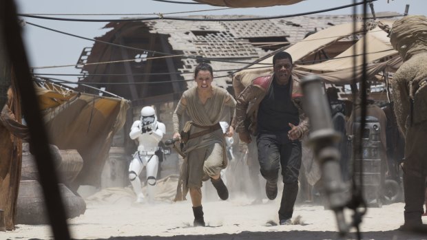 A stormtrooper chases Rey (Daisy Ridley) and Finn (John Boyega) in Star Wars: The Force Awakens.