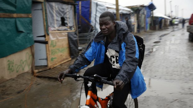 A migrant rides his bicycle through the  Calais camp.