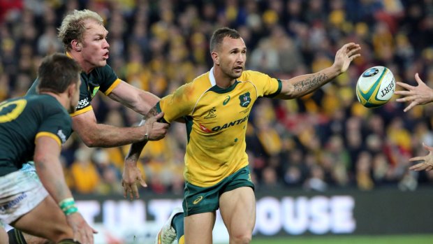 Australia's Quade Cooper, centre, is held by South Africa's Schalk Burger, left, as he passes the ball during their Rugby Championship match in Brisbane on Saturday.