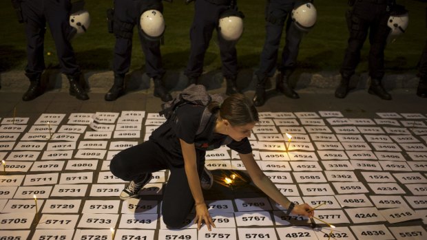 A woman lights candles between papers with numbers symbolising the victims of the 1995 Srebrenica massacre in downtown Belgrade, Serbia , on Friday. 
