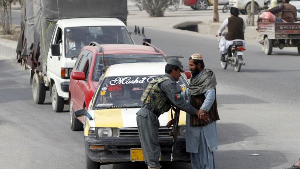 An Afghan policeman searches a passenger at a checkpoint in Kandahar earlier this month.