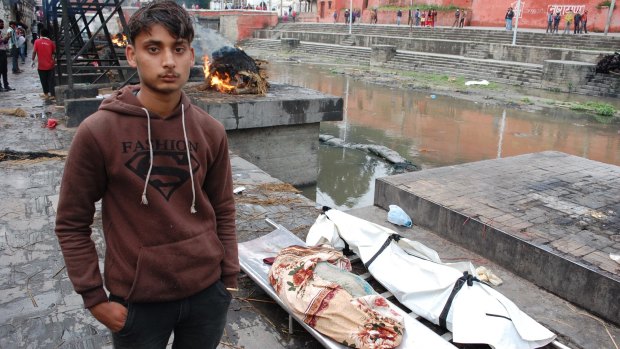Jagat Nath Thakur, 19, stands with the body of his sister, 9, and nephew, 10, killed when a building collapsed during the Nepalese earthquake.