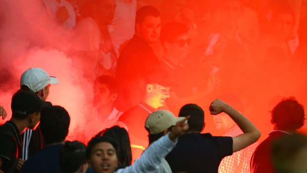 A supporter removes a flare after it was ignited in the Melbourne Victory active support area.