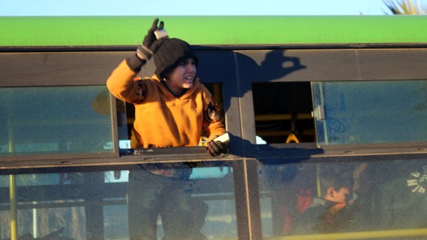 A boy stands inside a green government bus arriving in western rural Aleppo, Syria, as part of an evacuation deal.