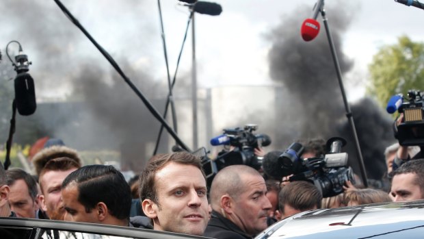 Emmanuel Macron, center, leaves the Whirlpool home appliance factory in Amiens on Wednesday.