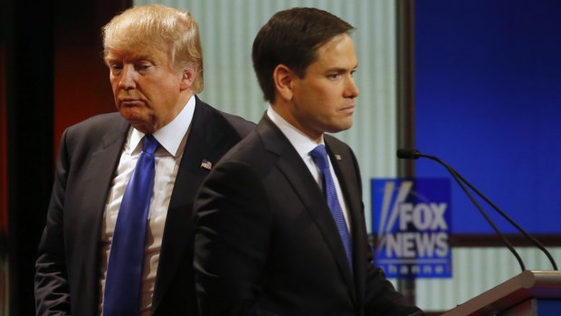 Donald Trump passes behind Senator Marco Rubio, during a Republican presidential primary debate at Fox Theatre on Thursday, March 3, 2016.