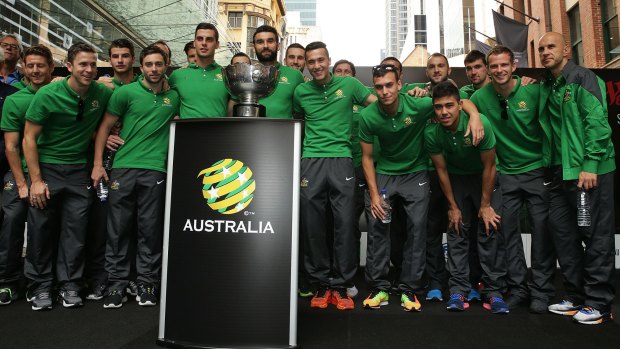Rising to the occasion: The Socceroos pose with the Asian Cup during celebrations at Westfield Sydney on Sunday.