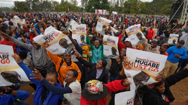 Protesters hold posters asking President Mugabe to step down, on which one has handwritten "37 years for nothing", at a demonstration at Zimbabwe Grounds in Harare.