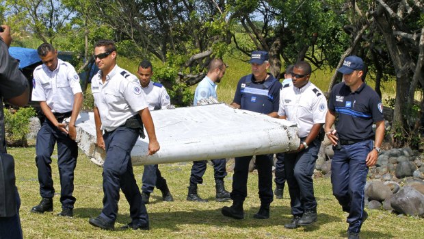 French police officers carry the piece of debris from a plane in Saint-Andre, Reunion Island.