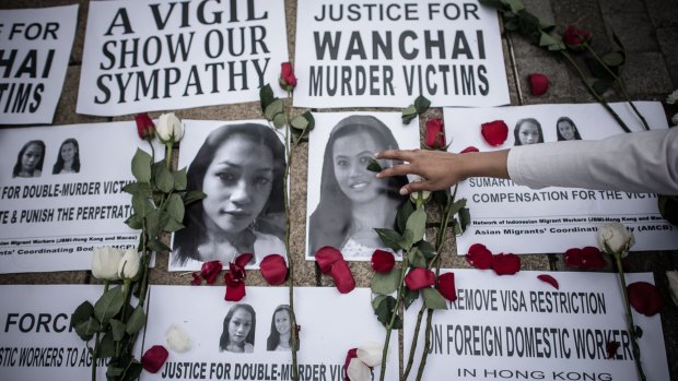 An Indonesian migrant worker lays rose petals over the pictures of murder victims in Hong Kong. 