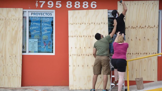 Christopher Rodriguez installs wood panels over a storefront window in preparation for Hurricane Irma in Carolina, Puerto Rico, on Tuesday.