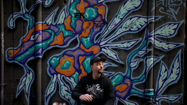 Social entrepreneur Ben Hoban wears a hoodie with a print of actual artwork of a sea dragon by artist Facter on the wall of Flinders Court, a laneway between Flinders Lane and Flinders Street.