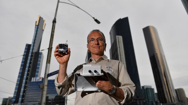 EPA expert Dr Anthony Boxshall holds a small air quality sensor, now installed on Queens Street Bridge lamps.