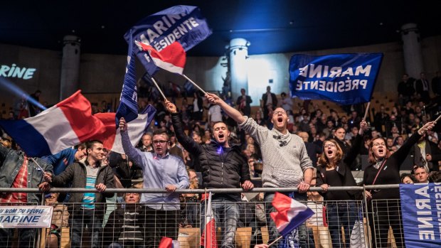 Attendees wave French national flags during an election campaign meeting with Marine Le Pen in Lille, France.
