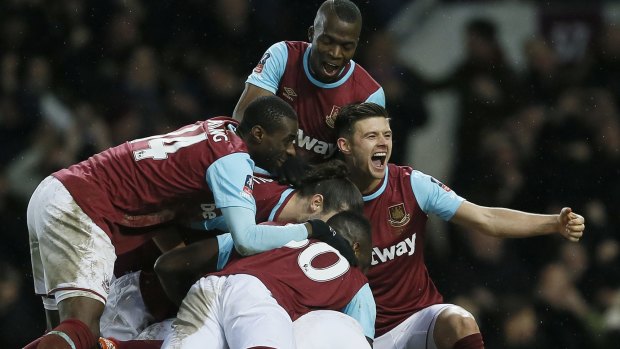 West Ham's Angelo Ogbonna (hidden) is swamped by teammates after scoring the winning goal against Liverpool.