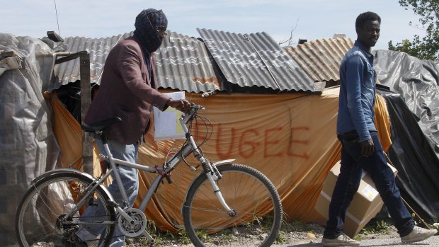 Migrants walk past a shelter at a makeshift camp known as the "jungle" in Calais, northern France.