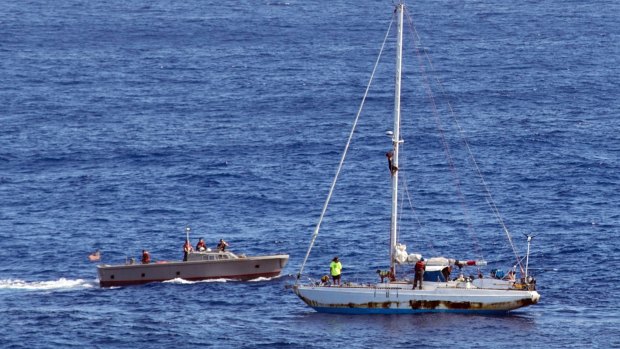 Sailors approach the stricken sailboat with two Honolulu women and their dogs aboard.