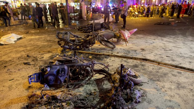 Wreckage of motorcycles are seen as security forces and emergency workers gather at the scene of a blast in central Bangkok on Monday.