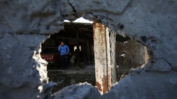 Shelling continues: A man is seen through a damaged wall in Donetsk.