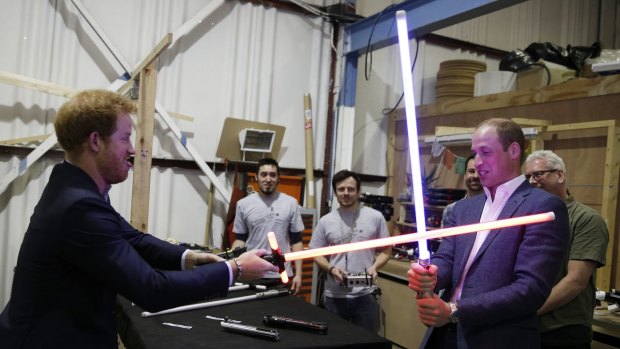 Prince Harry (left) and Prince William try out lightsabers during a tour of the <i>Star Wars</i> sets at Pinewood studios.