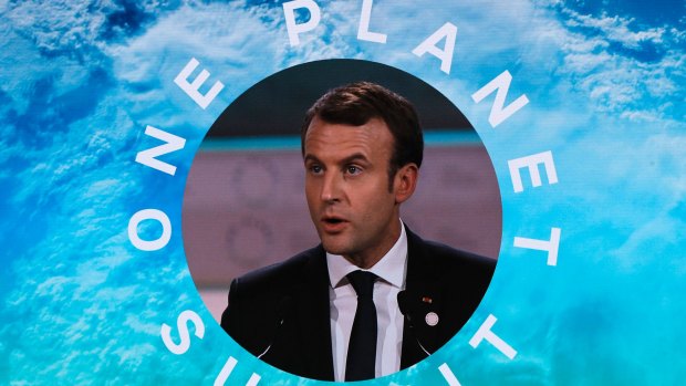 French President Emmanuel Macron is pictured on a screen as he delivers a speech at the One Planet Summit.