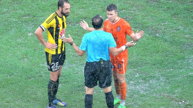 Roar captain Matt McKay debates with referee Alan Milliner after the match against Wellington Phoenix at Suncorp Stadium was called off due to heavy rain.