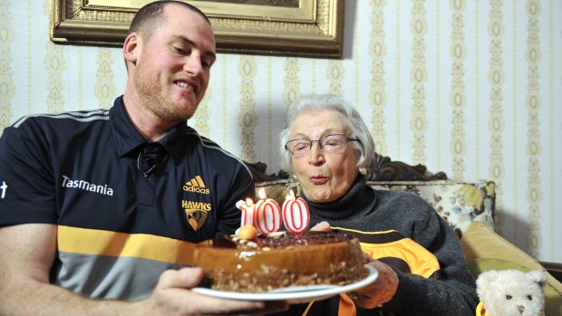 Happy birthday: Jarryd Roughead presents Eileen Grigg with a cake in Hawthorn colours.