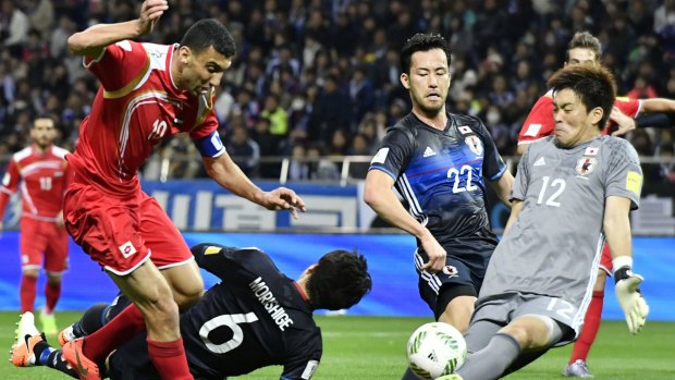Japan's goalkeeper Shusaku Nishikawa defends a shot on goal from Syria's Abdul Razak Al Hussein.