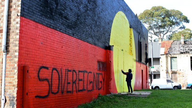 Aboriginal flag mural at Redfern's The Block reads 'sovereignty never ceded'. 