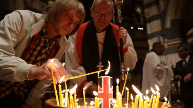 Melbourne children's book author Andy White, and his father, the Right Reverend Paul White, light a candle for the victims of the Manchester bombing at St Paul's Cathedral on Sunday.