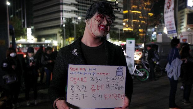 A protester in Seoul sporting a placard that reads: "Why do you need Halloween fest? We can see all the horror in our lives."
